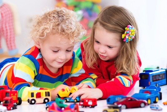 two preschool children playing trucks
